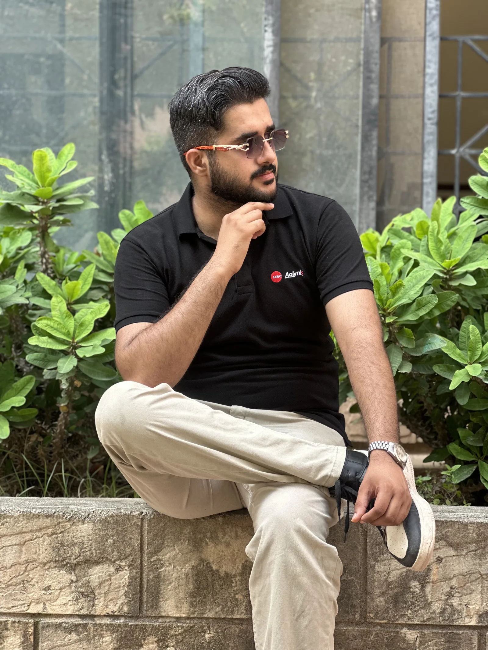 Ahmed sitting outdoors beside green plants, taking a quiet moment